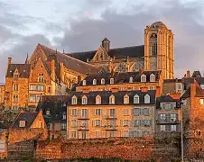 Cette vue magnifique montre la vieille ville du Mans, avec ses maisons à colombages et sa cathédrale Saint-Julien qui domine la cité. Les couleurs chaudes du coucher de soleil mettent en valeur le charme médiéval et l’authenticité de cette partie historique de la ville.